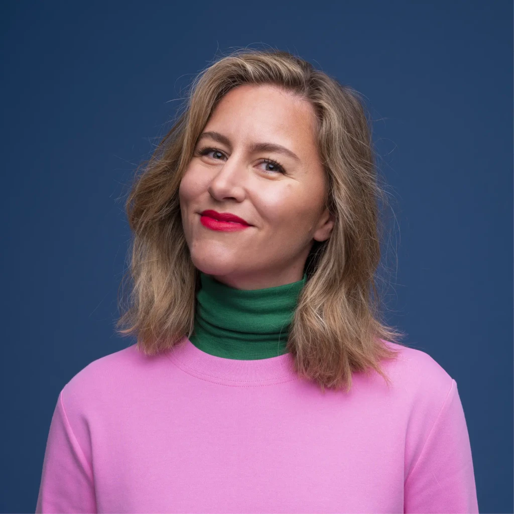 Cat Leo Dutch artist illustrator portrait based in Barcelona wearing pink and green on a blue background.